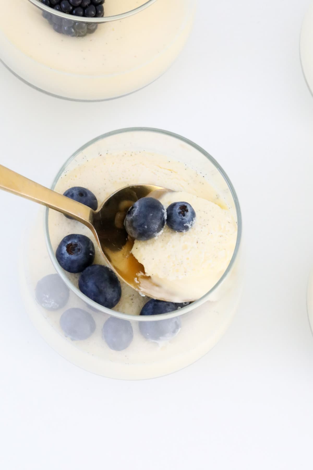 An overhead shot of a gold spoon in a creamy berry dessert.
