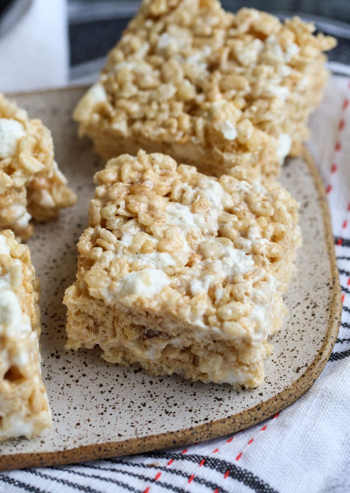 Brown Butter Pumpkin Spice Krispie Treats are the ultimate fall-time no bake dessert. You have a gooey, marshmallow-packed cereal bar made with super flavorful with browned butter and pumpkin spice! Rice Krispie Treats made with brown butter and pumpkin pie spice cut into squares on a plate