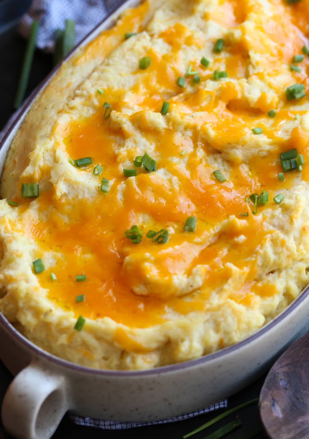 These Cheesy Baked Mashed Potatoes is the BEST mashed potato recipe ever! Melted cheddar cheese on top of baked mashed potatoes in a casserole dish