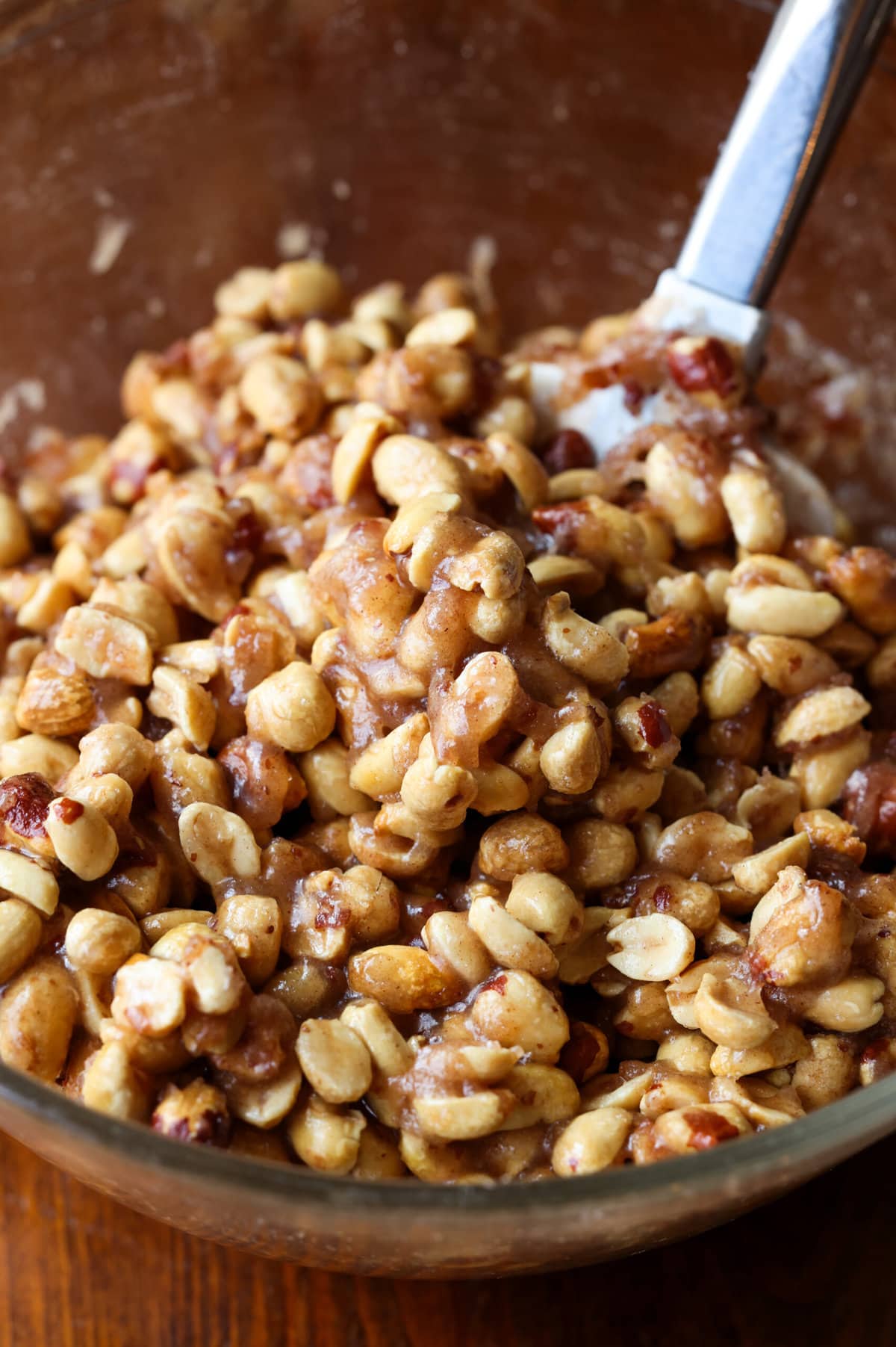 Crunchy, buttery, sweet, and salty roasted Butter Toffee Peanuts are easy to make and a great snack to enjoy or gift! Mixing peanuts in a bowl coating them with butter, sugar mixture