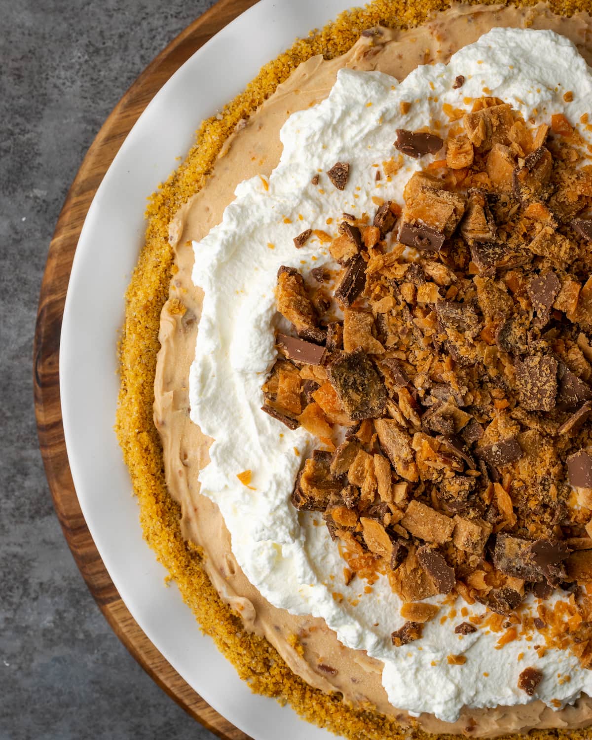 Creamy Butterfinger Pie is an easy dessert recipe that's loaded with Butterfinger candy bars! Treat yourself to this tasty peanut butter pie! Top view of Butterfinger pie garnished with whipped cream and chopped Butterfinger candy bars.