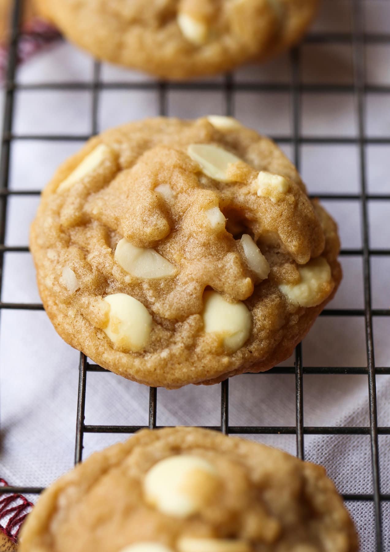 These white chocolate macadamia nut cookies are a classic. They have buttery, crisp edges with chewy centers loaded with creamy white chocolate and salty macadamia nuts. A white chocolate macadamia nut cookie on a wire rack