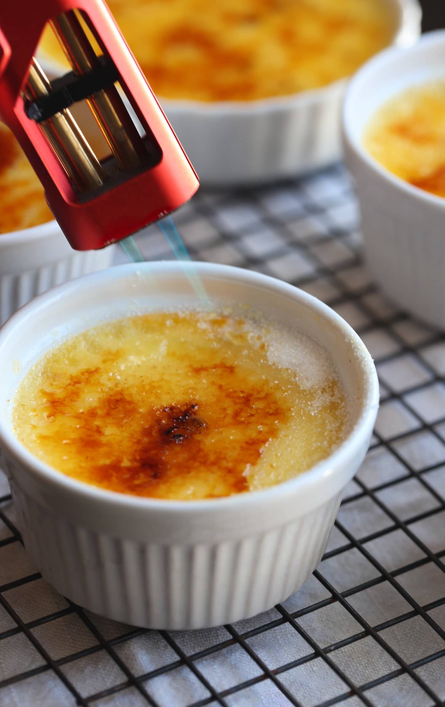 using a kitchen torch to brûlée the sugar, melting it and caramelizing so it forms a crispy sugar top