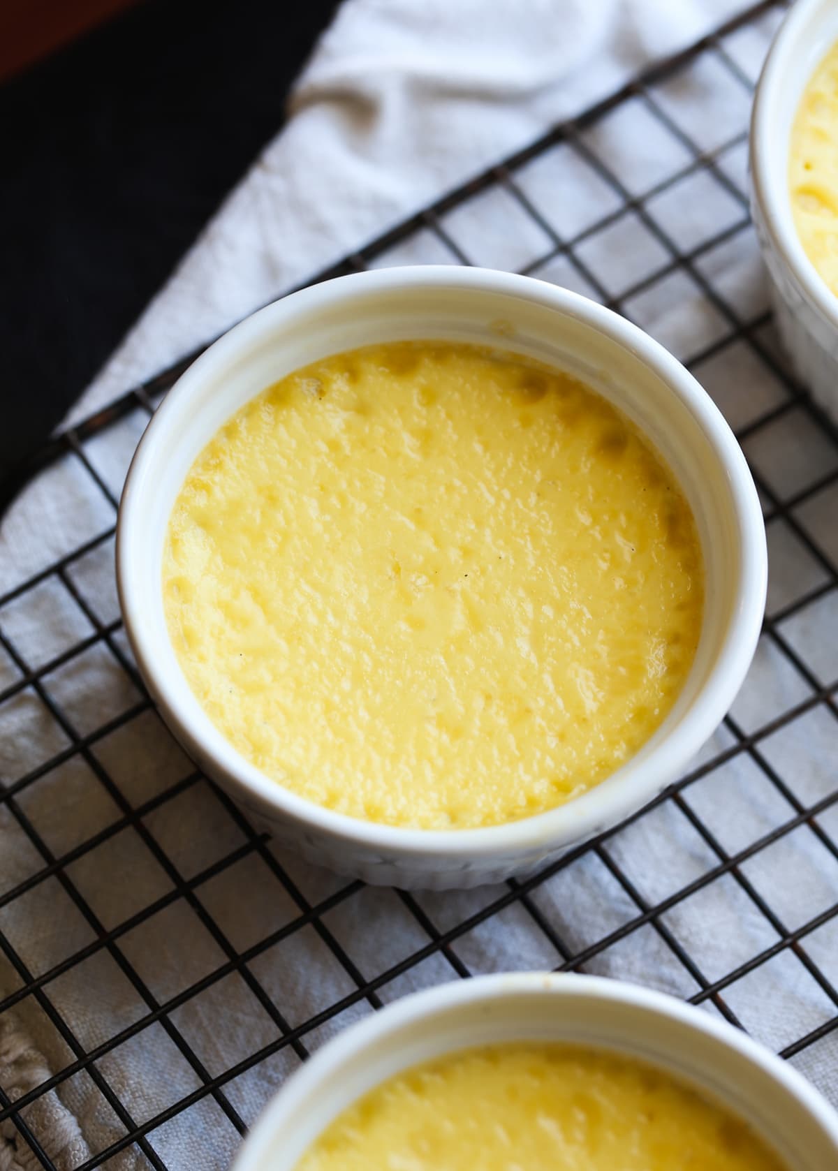 Custard baked in a white ramekin on a wire rack