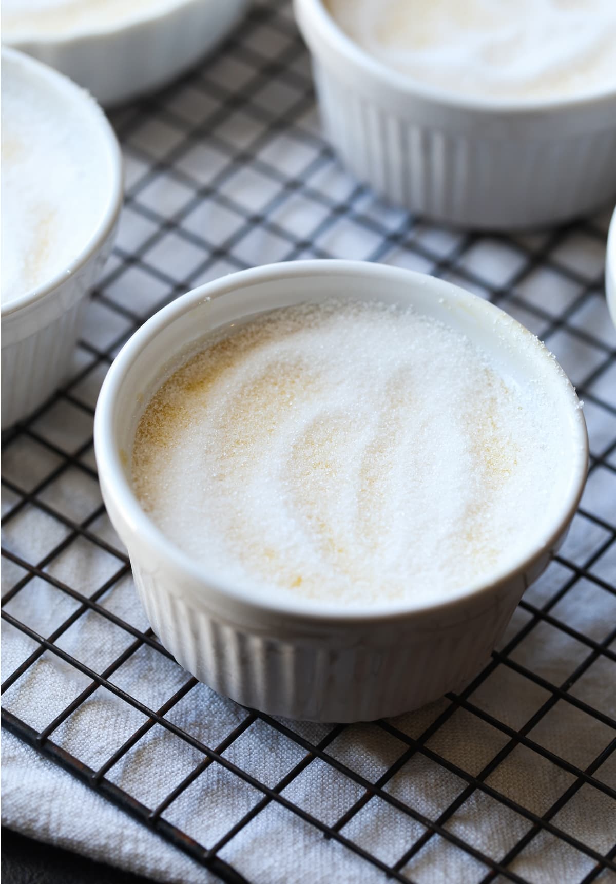 Granulated sugar on top of custard in a ramekin before using a food torch to melt the sugar