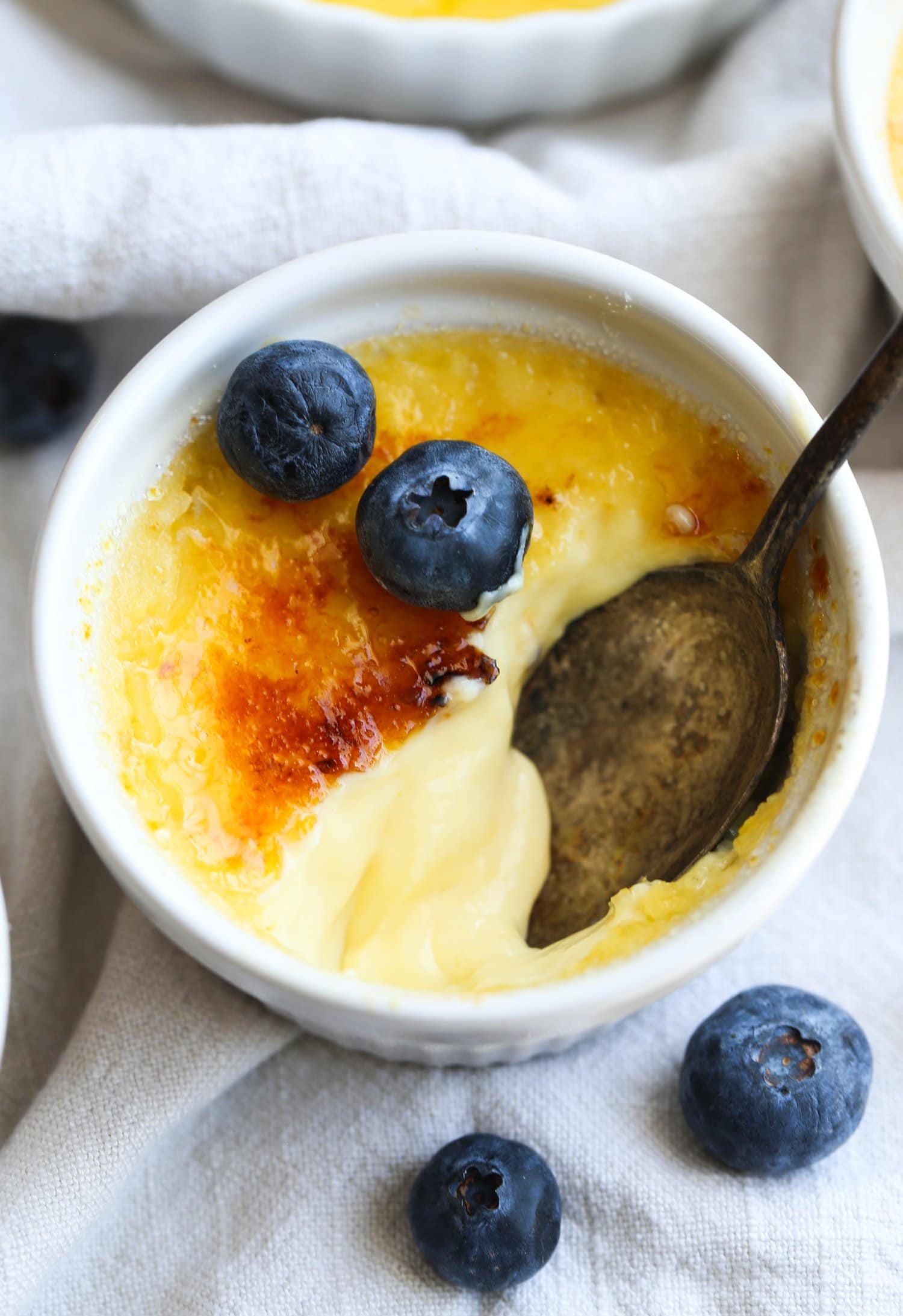 Vanilla custard with caramelized sugar on top broken in a dish with a spoon