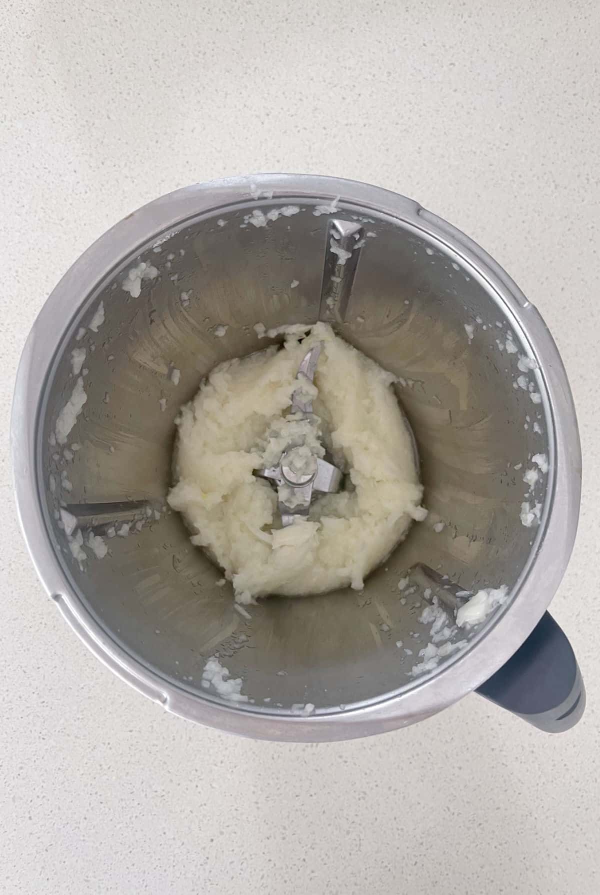 Grated onion in a Thermomix bowl.