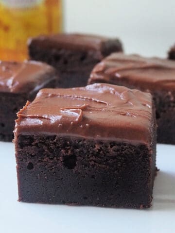 Side view of Kahlua Brownies on a white plate. There is a bottle of Kahlua in the background.