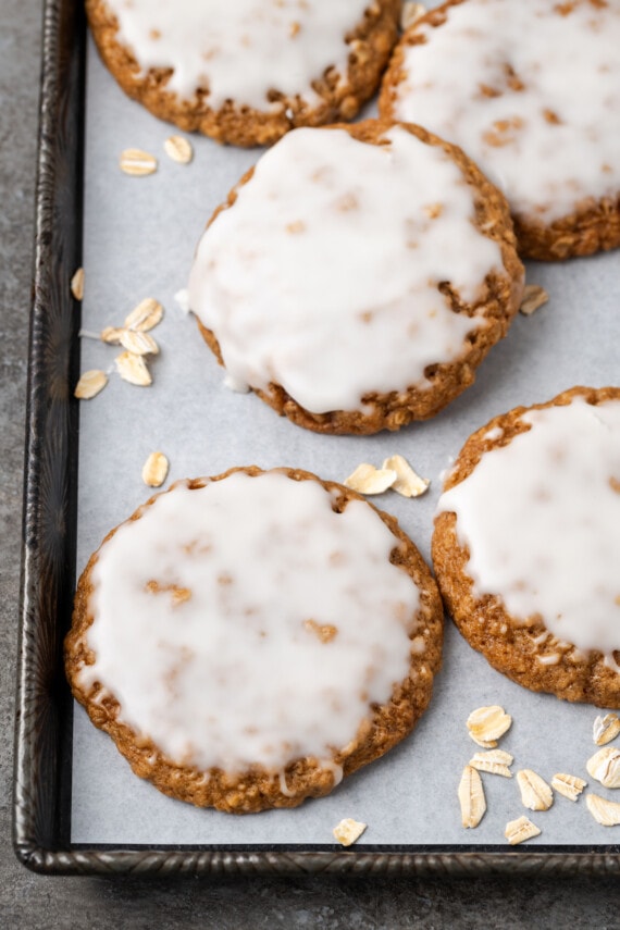 Close up of iced oatmeal cookies on a baking sheet.