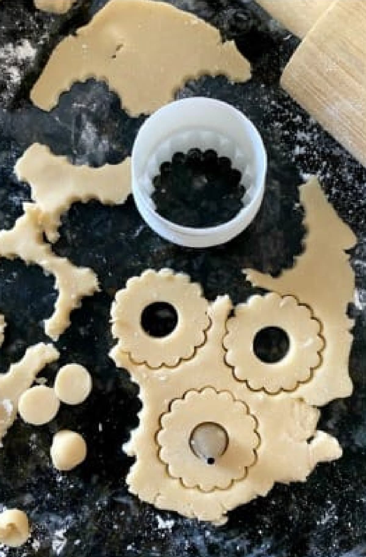 This is the absolute BEST Linzer Cookies recipe ever! These gorgeous and easy cookies are buttery, flaky shortbread filled with sweet jam and dusted with powdered sugar. A Christmas Cookie Classic! Cutting out dough to make Linzer Cookies