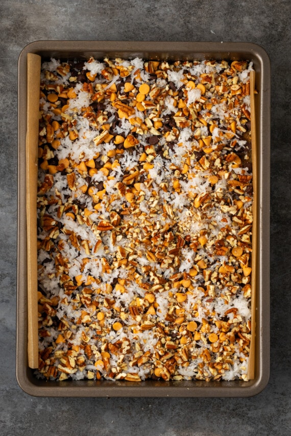 Magic bar ingredients assembled in a lined baking pan.