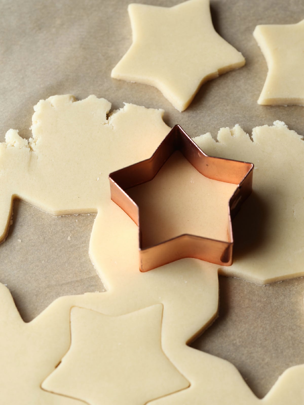 cutting out sugar cookie dough with a star shaped cookie cutter