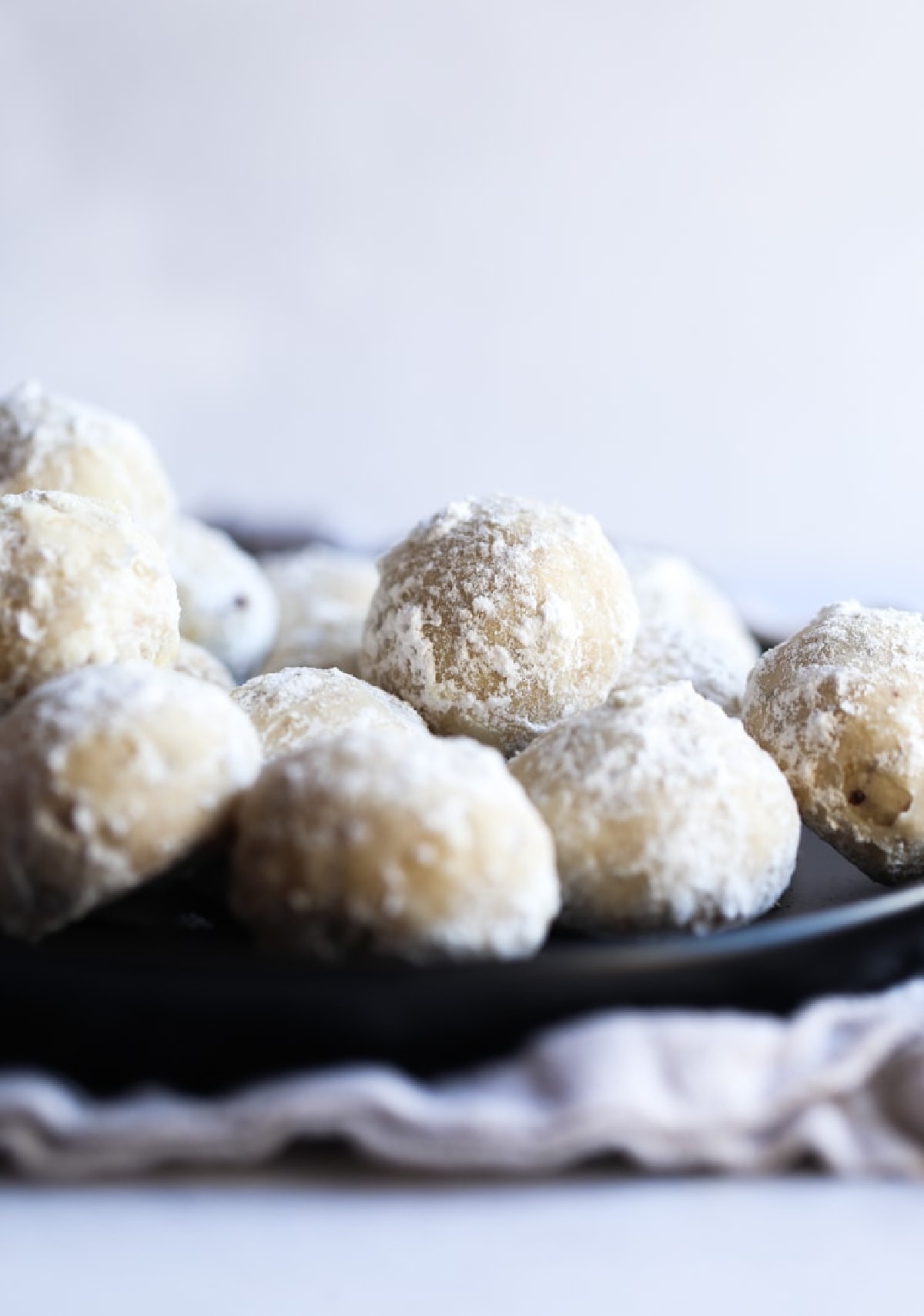 Russian tea cakes (also called snowball cookies) are rich and buttery holiday cookies coated in powdered sugar, filled with walnuts or pecans! Russian Tea Cakes stacked on a plate