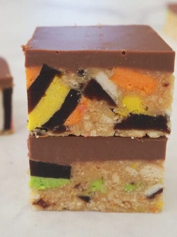 Two pieces of Licorice Allsort slice sitting on top of each other on a marble bench.