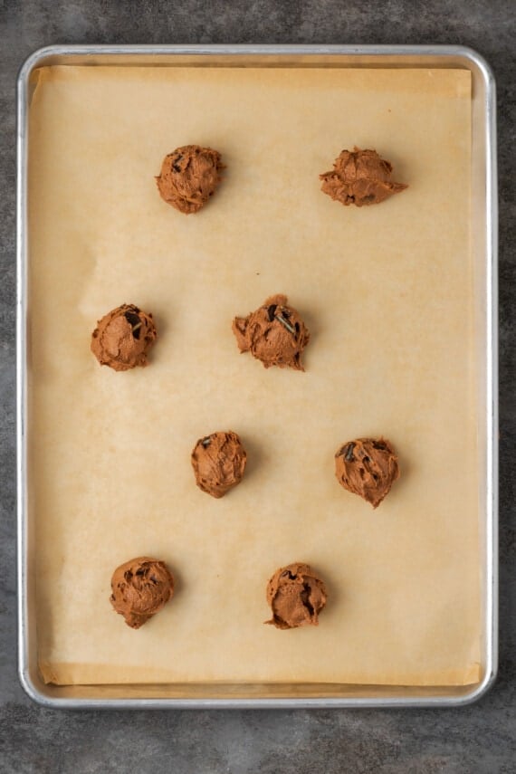 Scoops of double chocolate mint cookie dough on a parchment-lined baking sheet.
