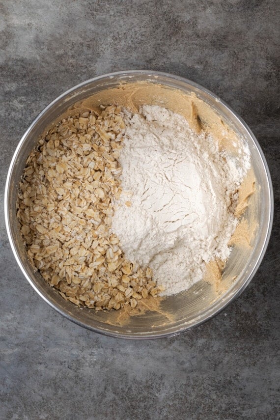 Soft and chewy oatmeal butterscotch cookies are rich and buttery, filled with tender oats, butterscotch morsels, and sweet cinnamon spice. Oats and dry ingredients added to creamed butter and sugar in a mixing bowl.