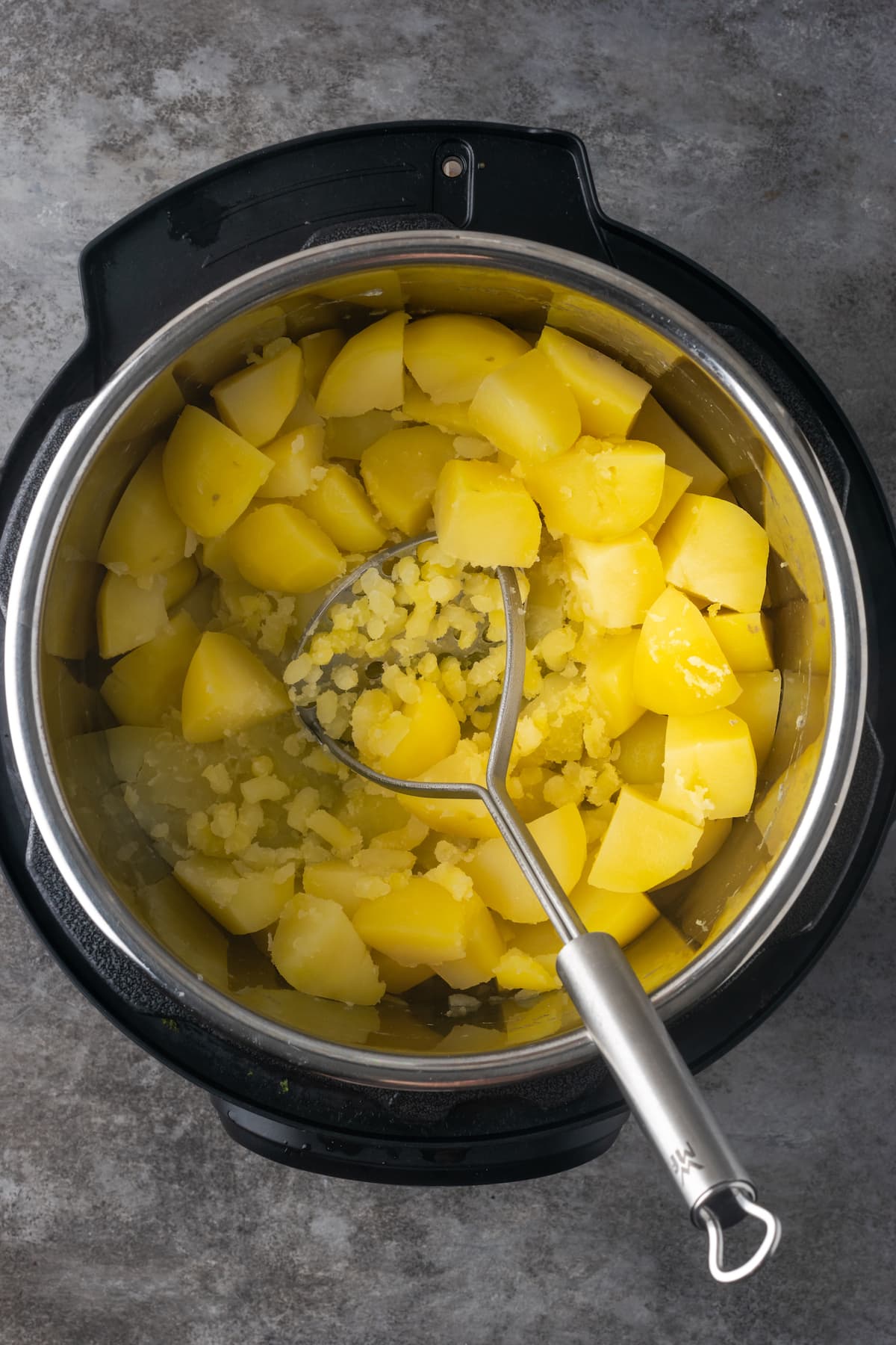 Buttery, fluffy Instant Pot Mashed Potatoes are a flavorful and easy side dish. Enjoy creamy homemade mashed potatoes, ready in half the time! A potato masher is used to mash cooked chopped potatoes inside an Instant Pot.