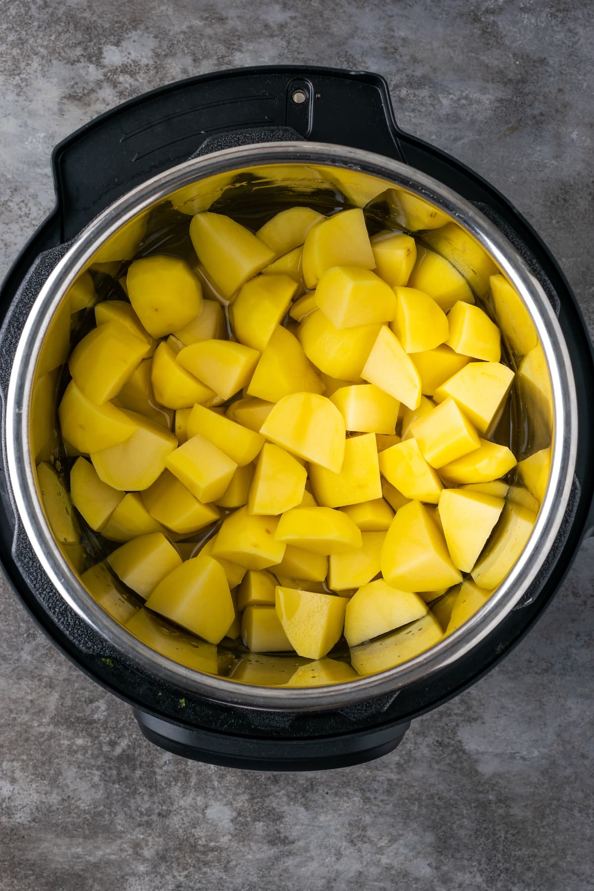 Buttery, fluffy Instant Pot Mashed Potatoes are a flavorful and easy side dish. Enjoy creamy homemade mashed potatoes, ready in half the time! Chopped cooked potatoes inside an Instant Pot.