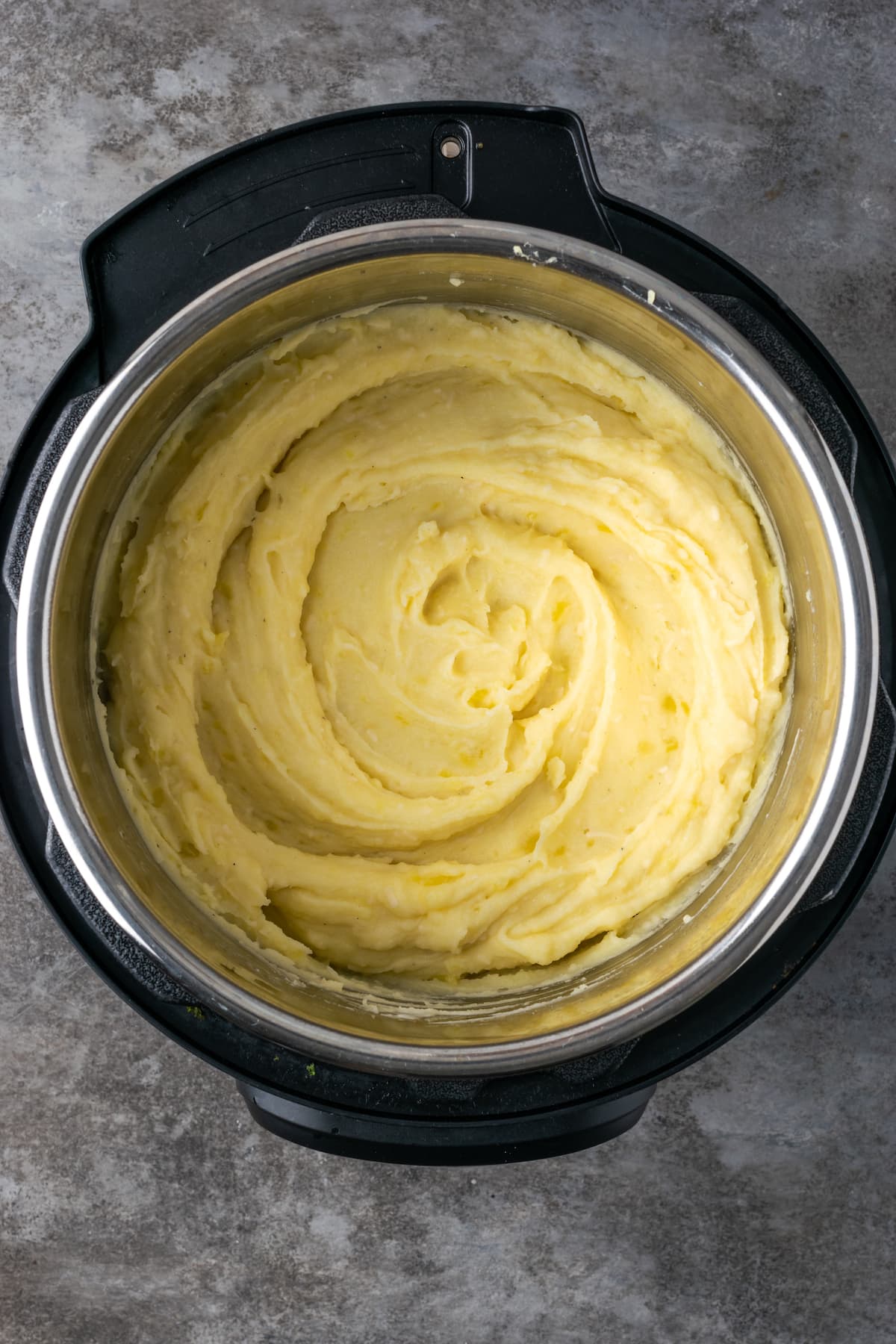 Buttery, fluffy Instant Pot Mashed Potatoes are a flavorful and easy side dish. Enjoy creamy homemade mashed potatoes, ready in half the time! Overhead view of finished Instant Pot mashed potatoes inside the pressure cooker.