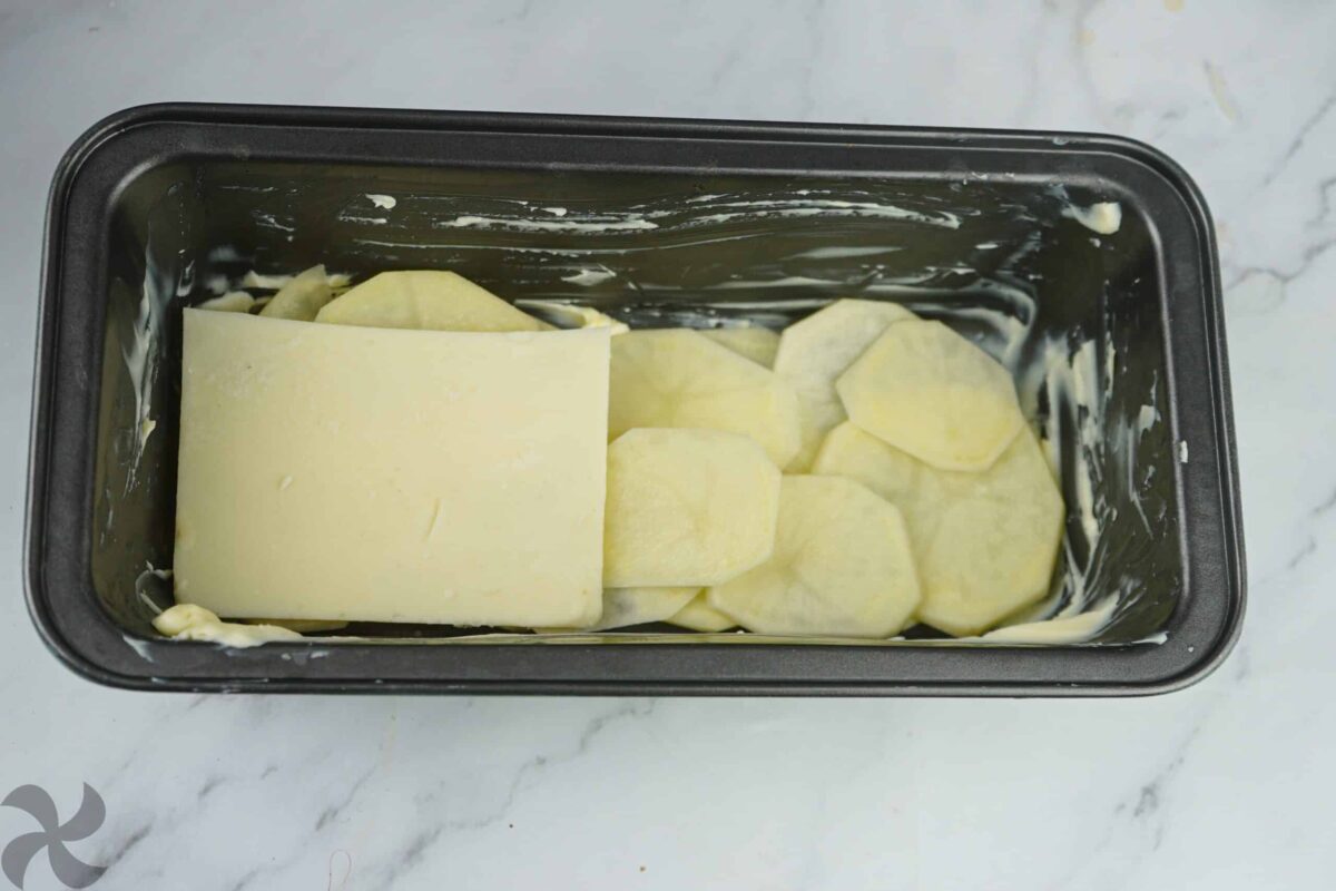 Colocamos la primera capa de patata, seguido del queso