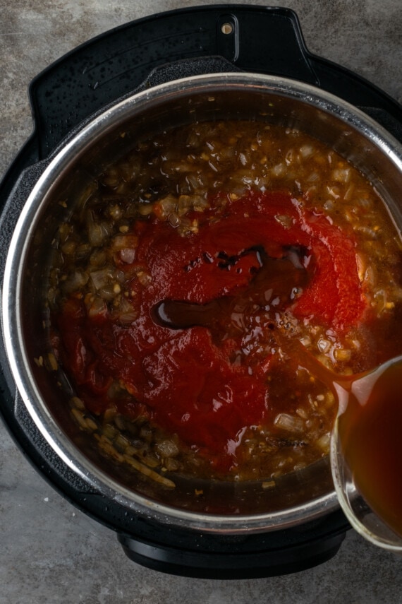 Additional broth is poured in to the caramelized onions in the instant pot.