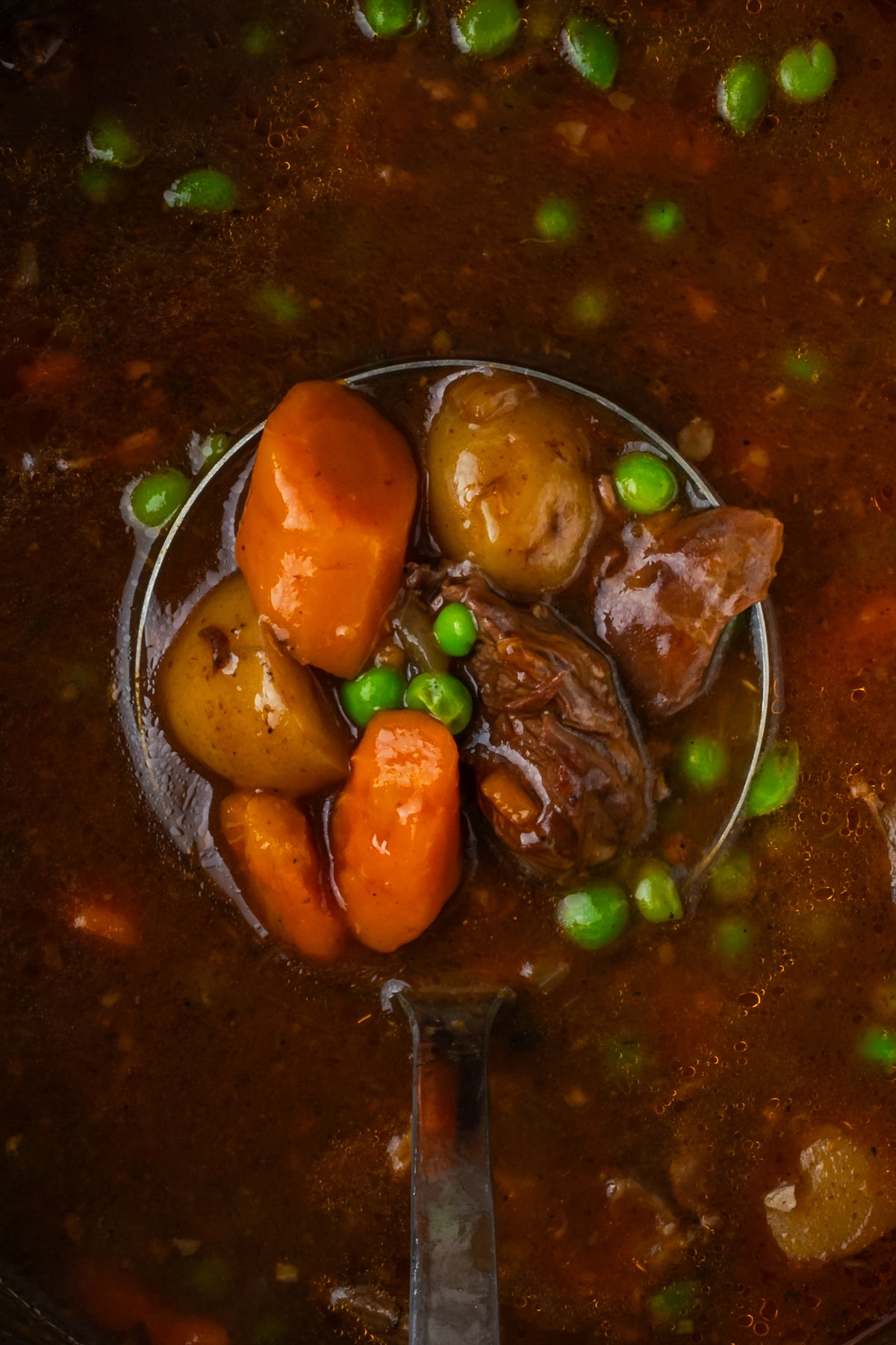 Closeup overhead view of a ladleful of beef stew held above the instant pot.