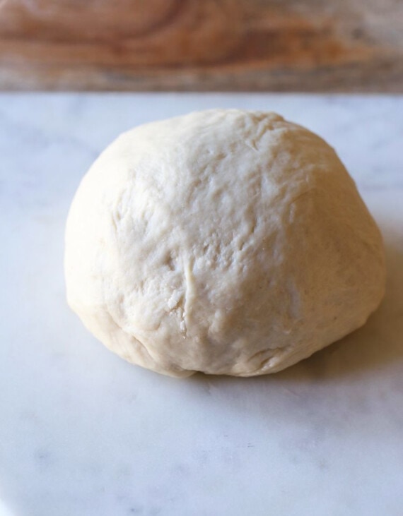 A ball of pizza dough on a countertop.