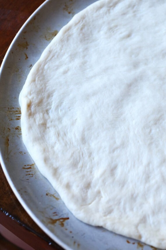 Pizza dough spread out on a round pan.
