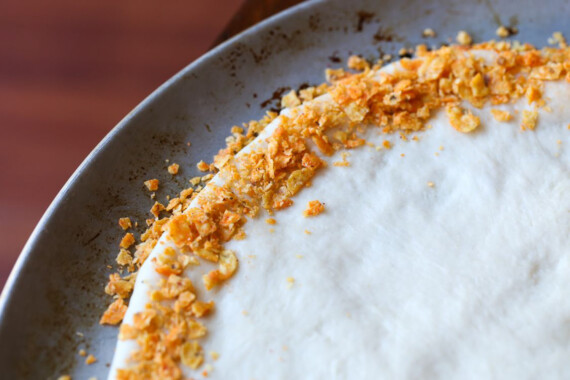 Tortilla chips pressed into the outside edge of an unbaked pizza crust.