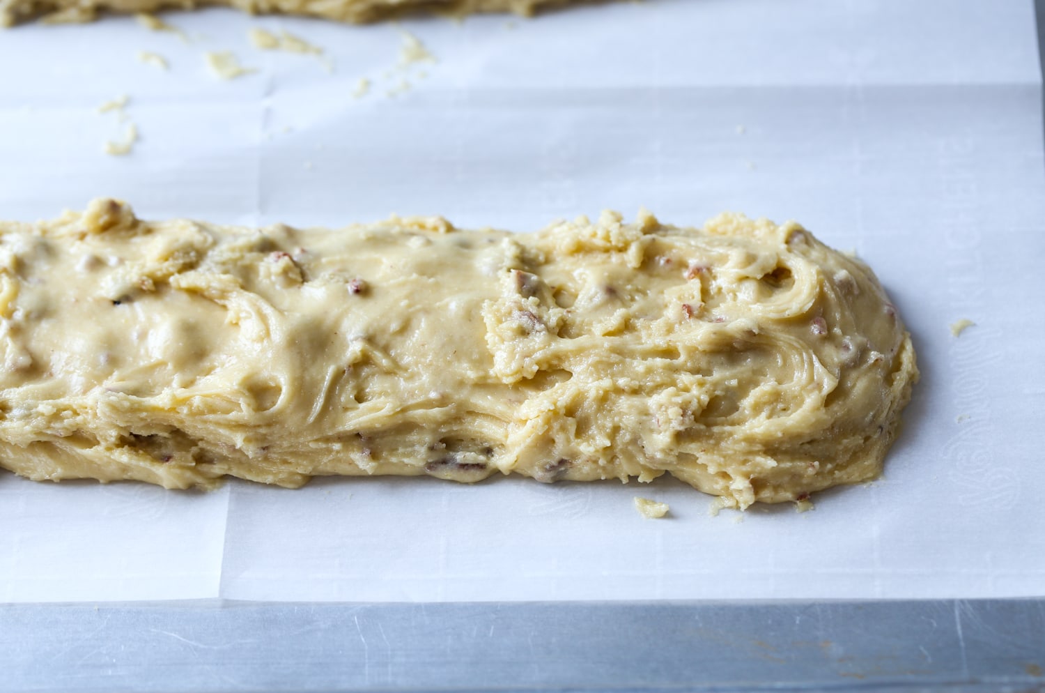 This classic Italian Biscotti recipe is super easy to make and totally customizable! Add sliced almonds or dip them in chocolate! Unbaked cookie log with pecans.
