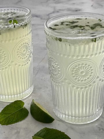 Two Thermomix Mojitos in decorative glasses on a marble top.