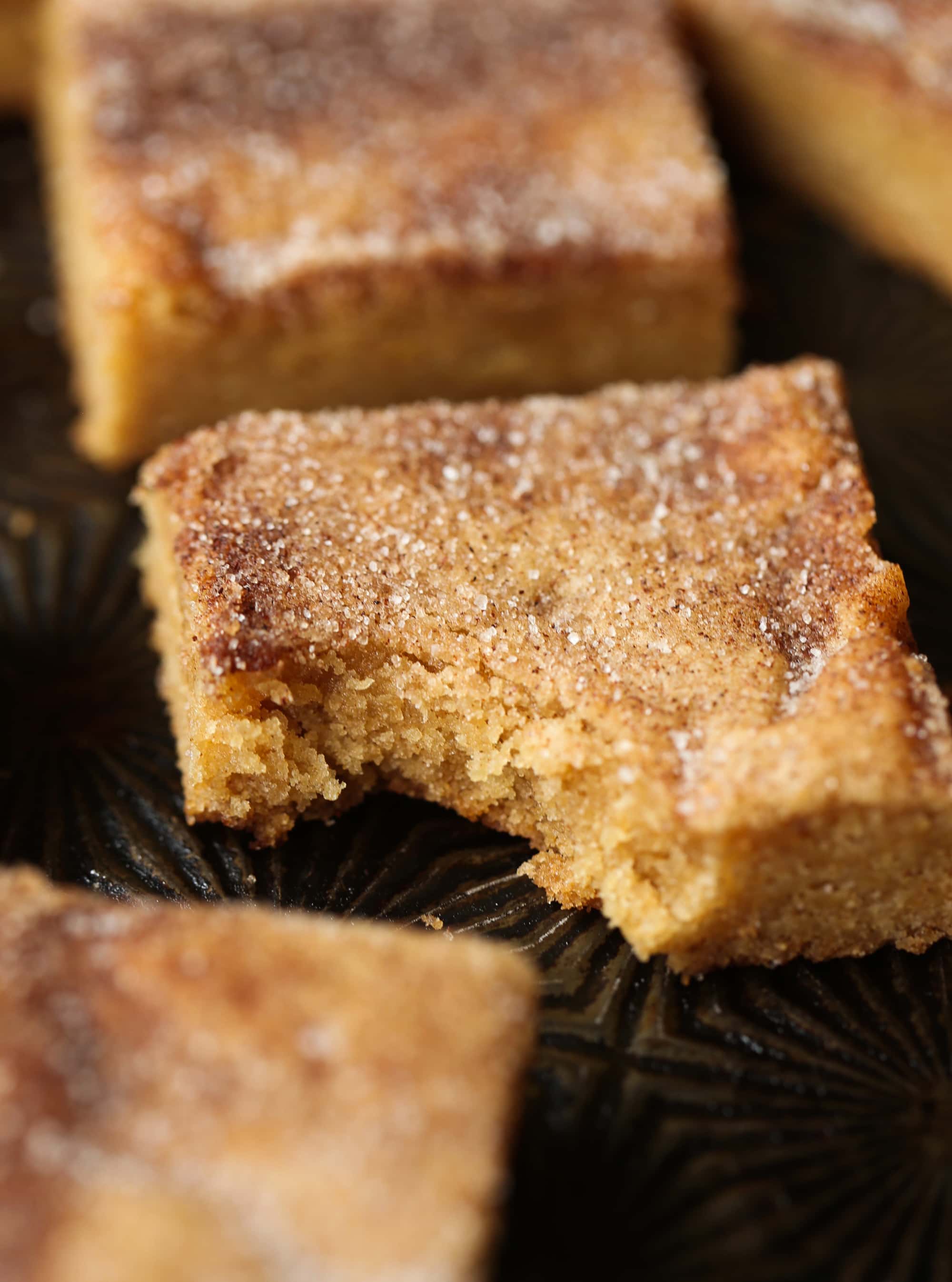 Buttery, chewy cookie bars that taste just like a churro! A cinnamon sugar cookie bar with a bite taken out on a baking sheet