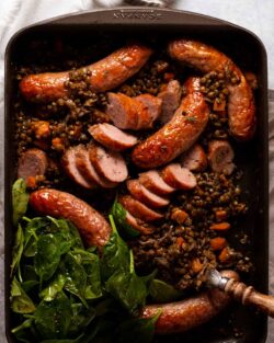 Salchichas y lentejas al horno en una sartén