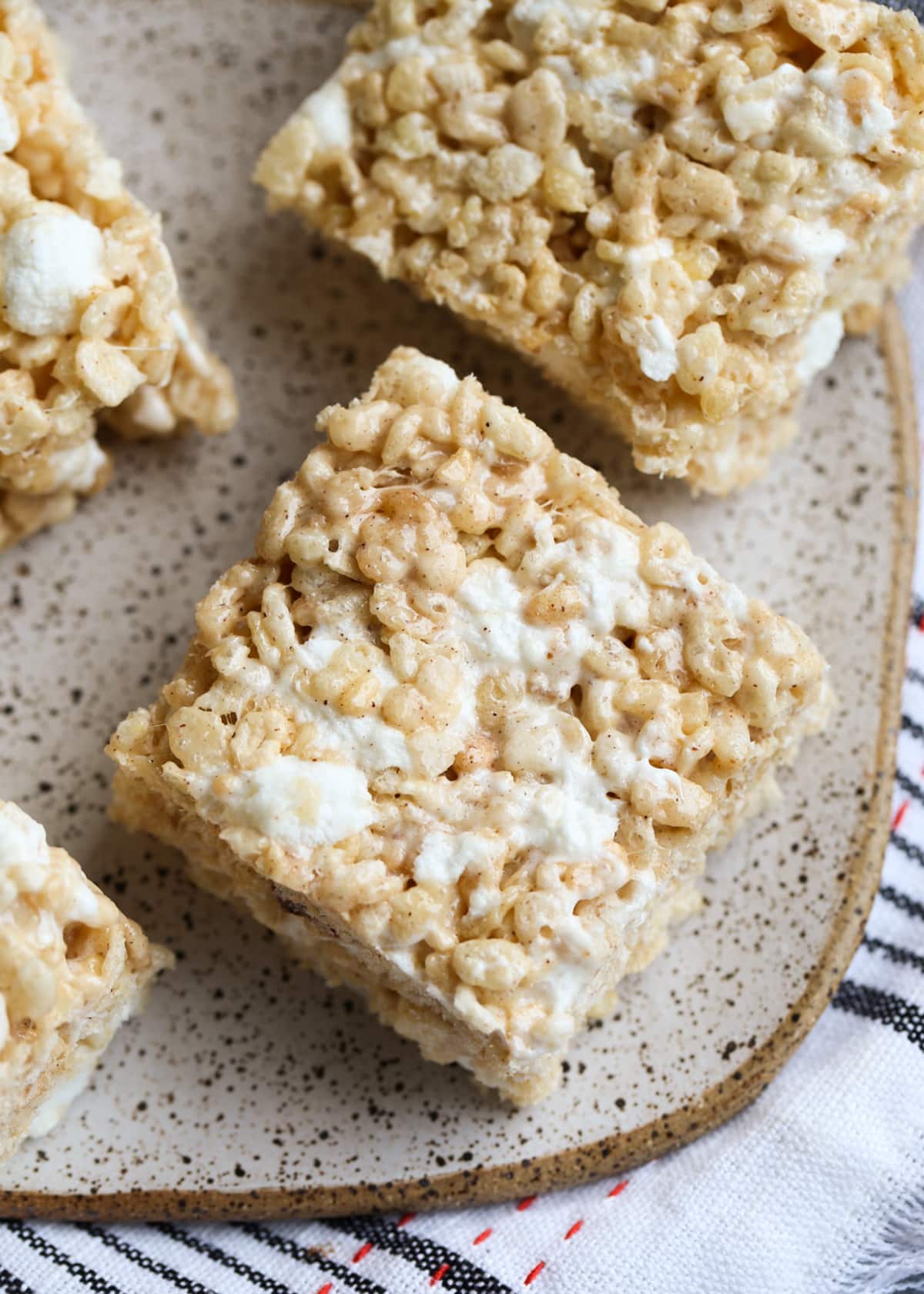 Brown Butter Pumpkin Spice Krispie Treats are the ultimate fall-time no bake dessert. You have a gooey, marshmallow-packed cereal bar made with super flavorful with browned butter and pumpkin spice! Pumpkin Spice Krispie Treats on a plate from above showing gooey marshmallow