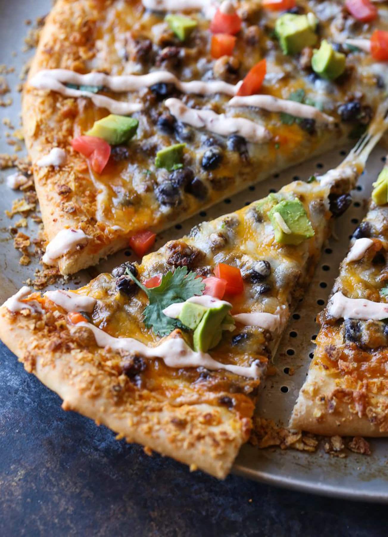 Close up of a taco pizza cut into slices on a pizza pan.