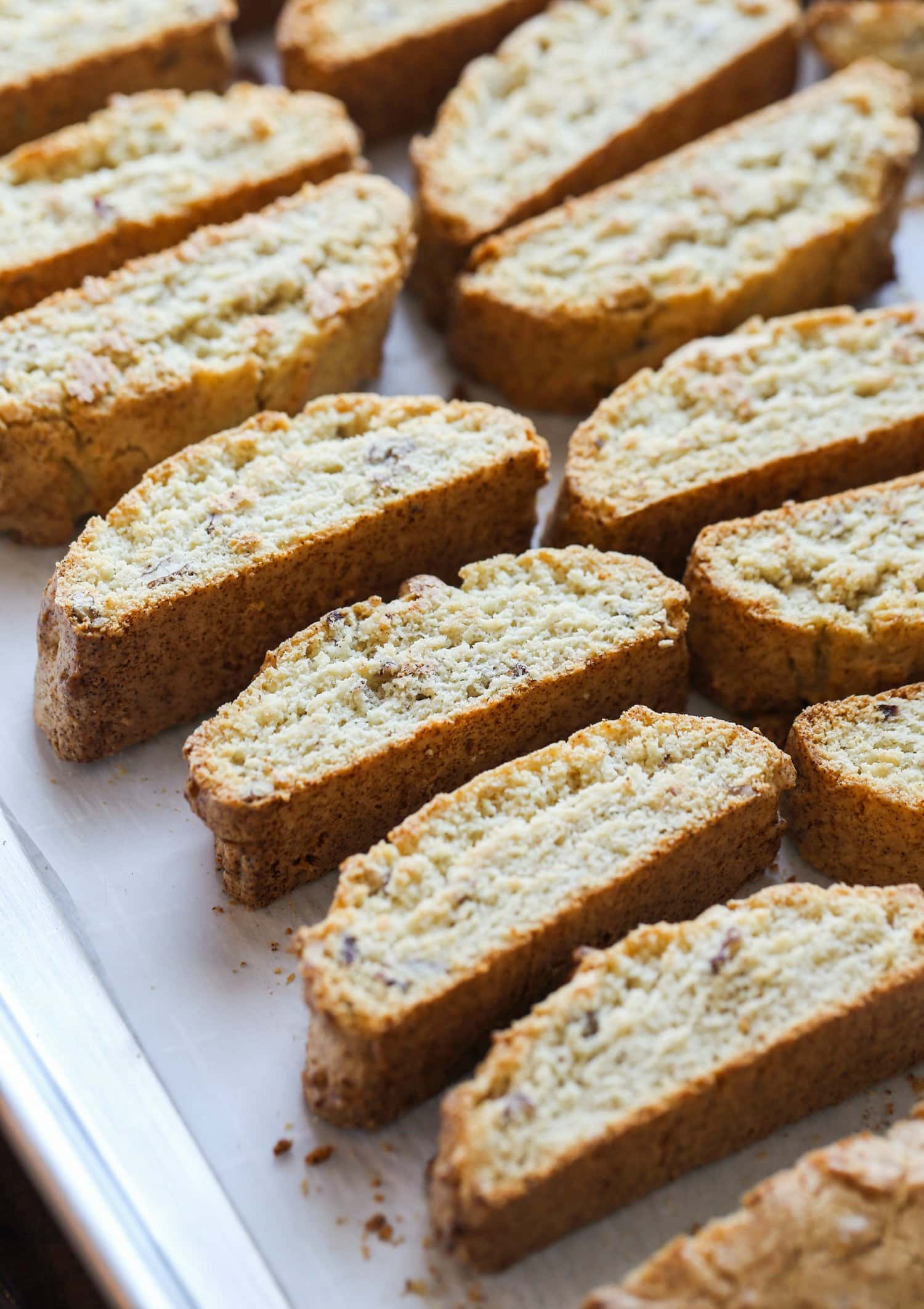 This classic Italian Biscotti recipe is super easy to make and totally customizable! Add sliced almonds or dip them in chocolate! Rows of sliced biscotti cookies.